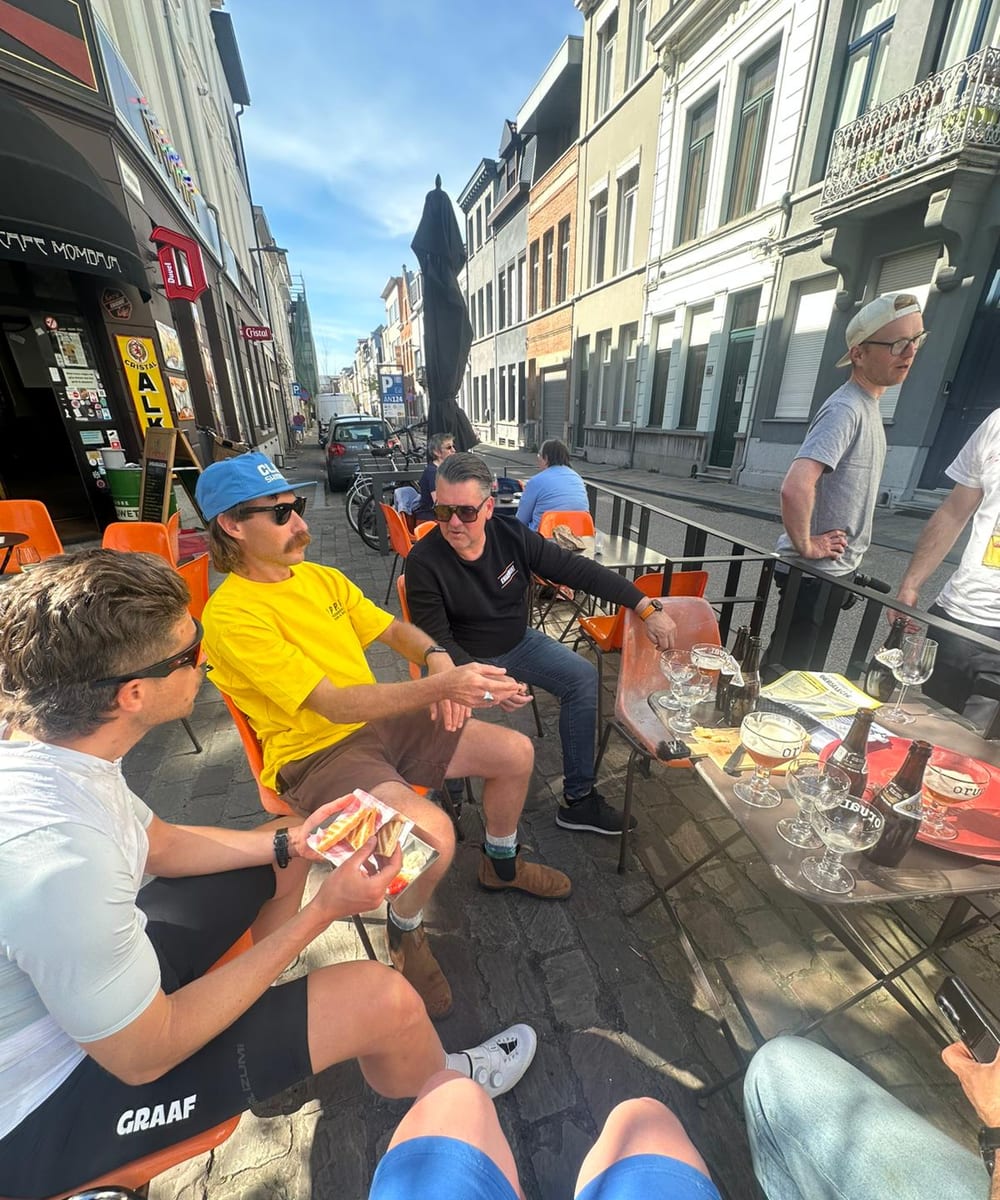 Cyclists sharing beers and food outside a Belgian cafe